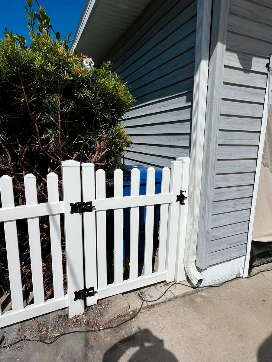 White PVC picket gate beside a home