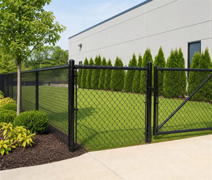 Black chain link fence and gate beside a landscaped property